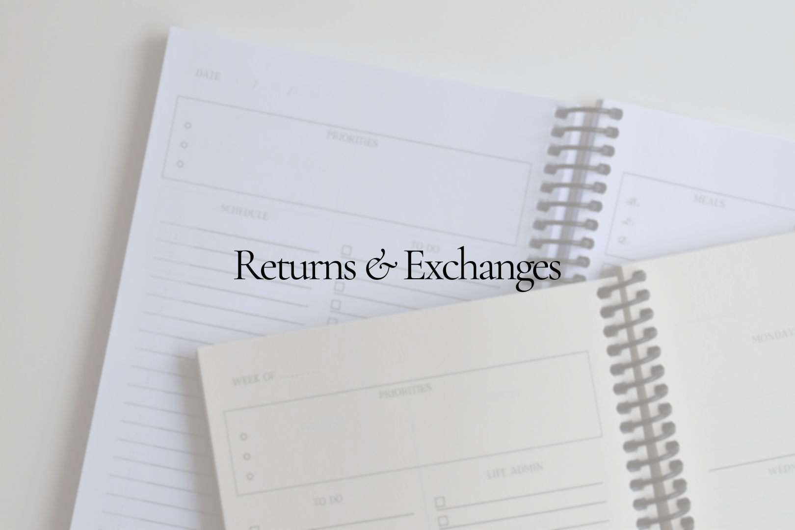 Two open spiral planners stacked on top of each with overlay text "Returns & Exchanges"