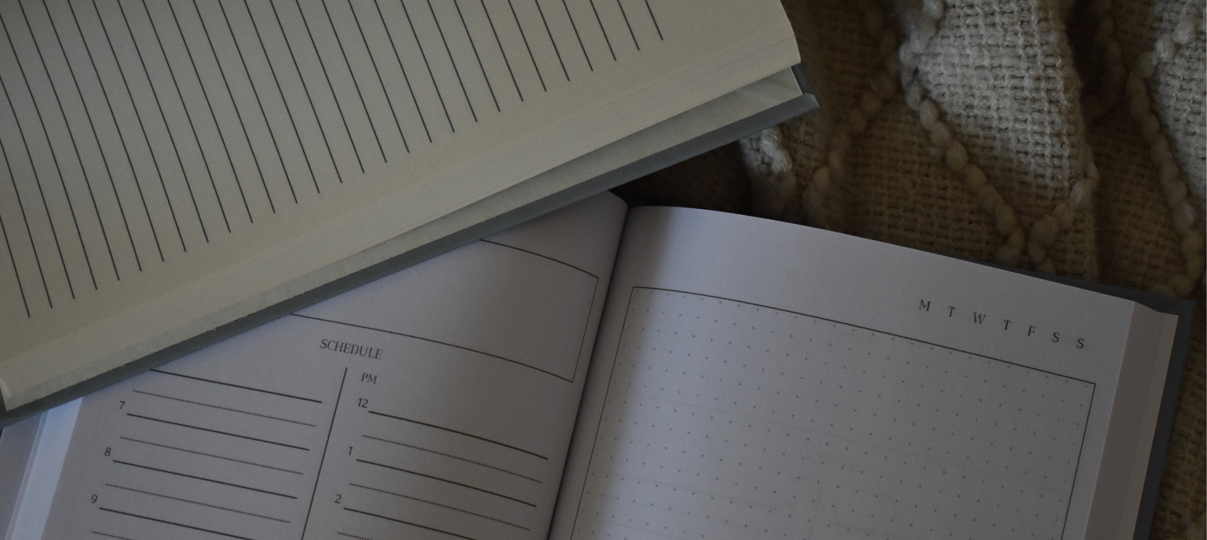Open planners and journals with custom layouts on a cozy throw blanket