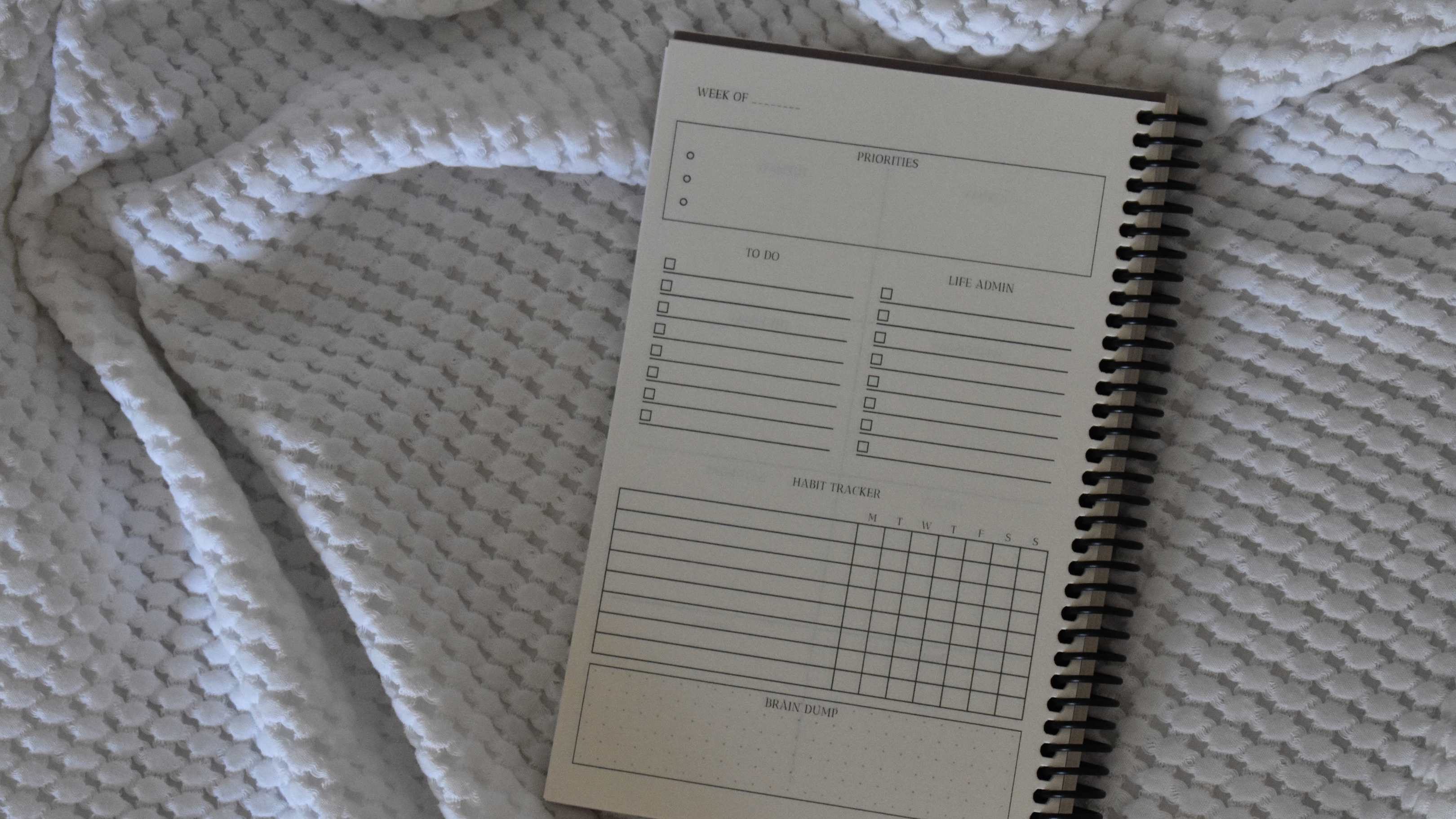 Custom planner or journal with coil or spiral binding on a white cozy blanket