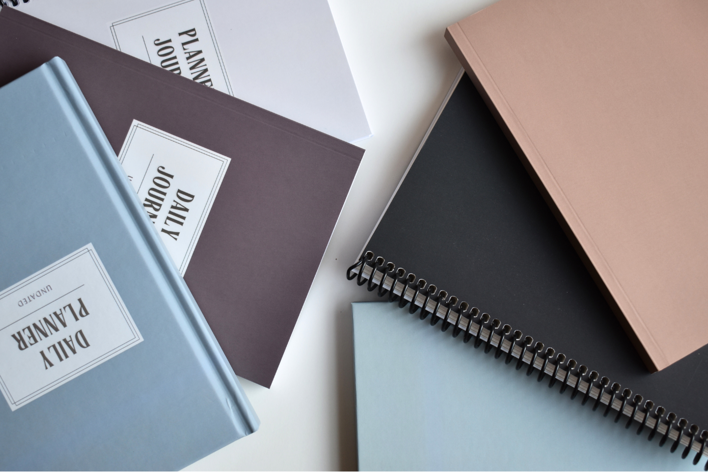 Collection of planners and journals in various colors, some with simple texts on cover
